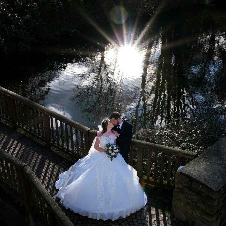 hochzeitsfotograf nordkirchen, fotoshooting hochzeit nordkirchen, brautpaar küsst sich auf einer brücke am schloss nordkirchen