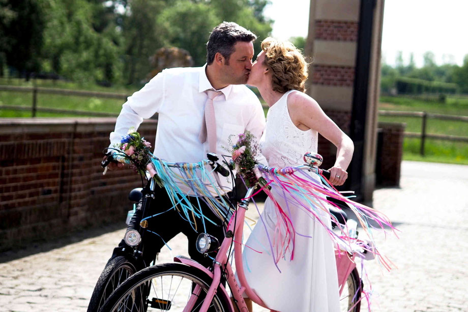 hochzeitsfotograf nordkirchen, fotoshooting hochzeit nordkirchen,heiraten am schloss nordkirchen, brautpaar auf geschmückten fahrrädern vor dem schloss nordkirchen
