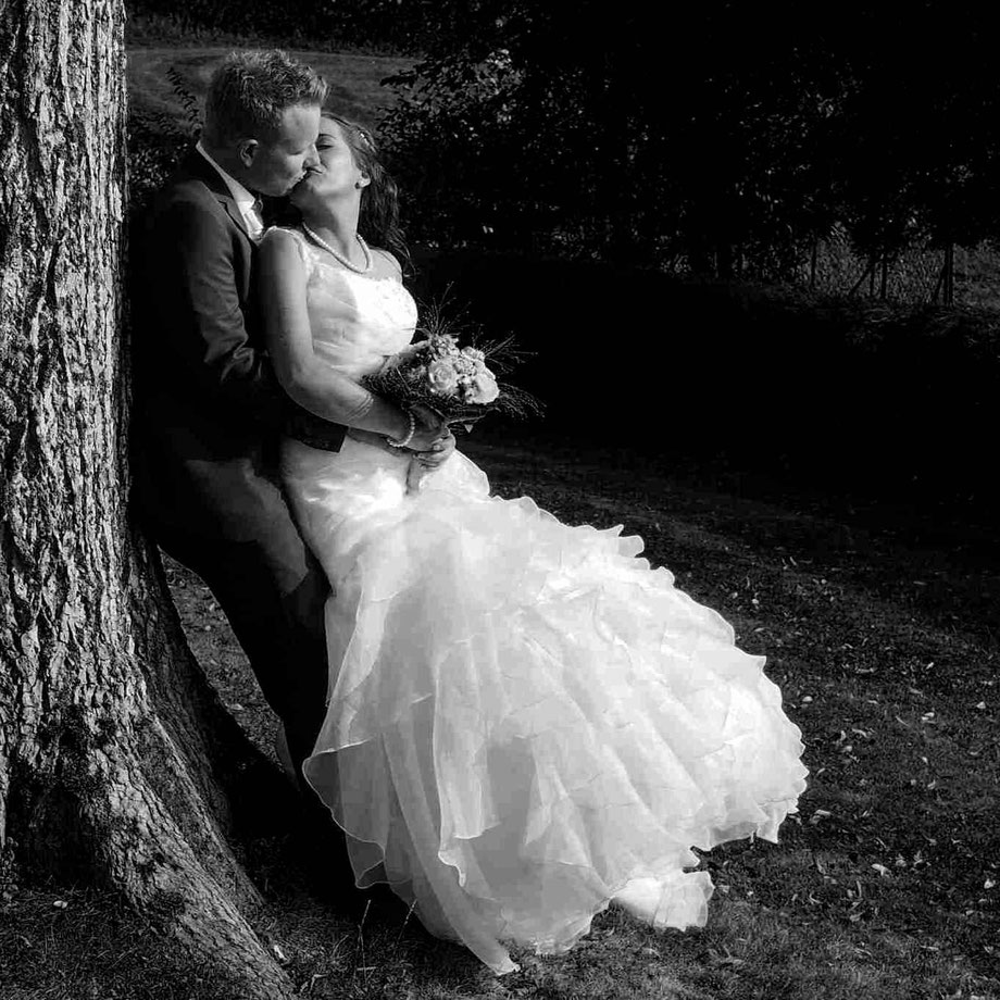 hochzeitsfotograf wil hangebrauck, brautpaar küsst sich an einem baum lehnend, schwarzweiss-foto