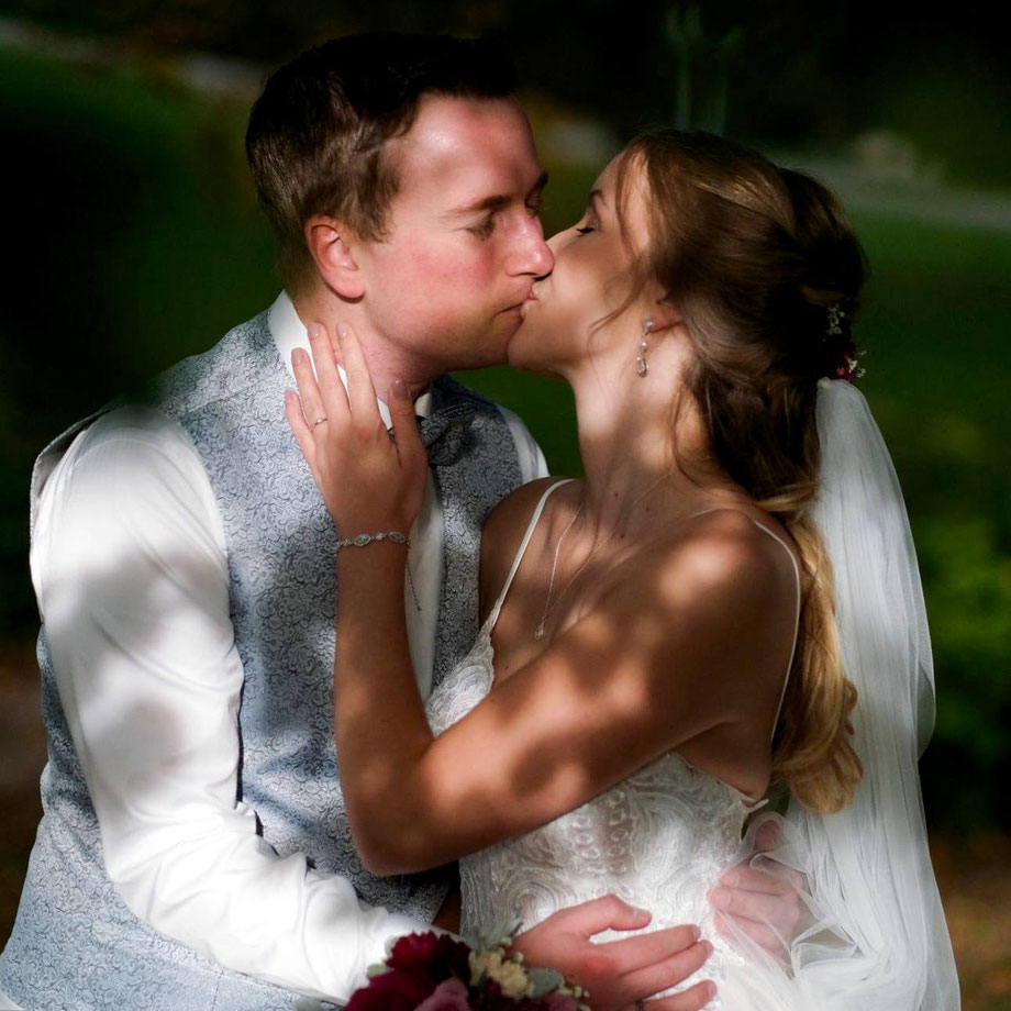 hochzeitsfotograf wil hangebrauck, brautpaar küsst sich im licht- und schattenpiel einer waldlichtung